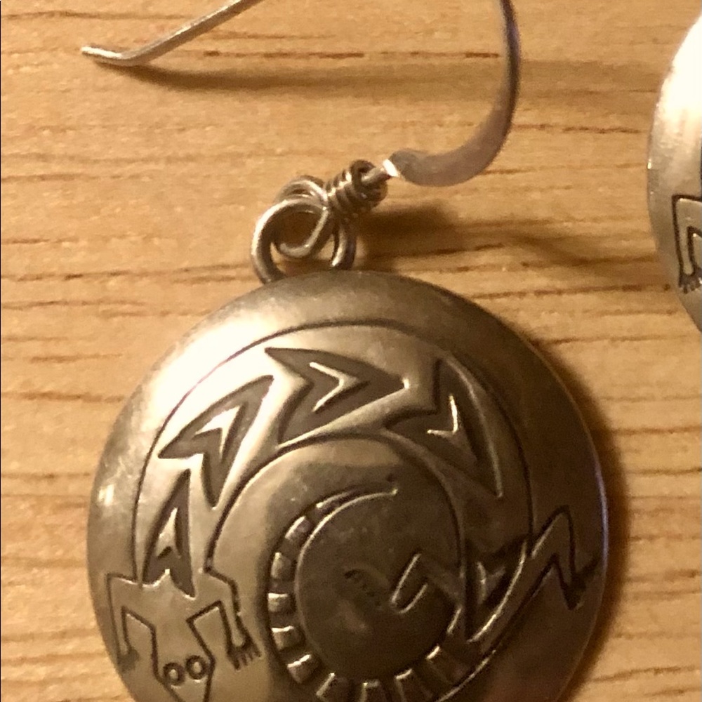 Silver dime shape earrings with gecko or lizard design.